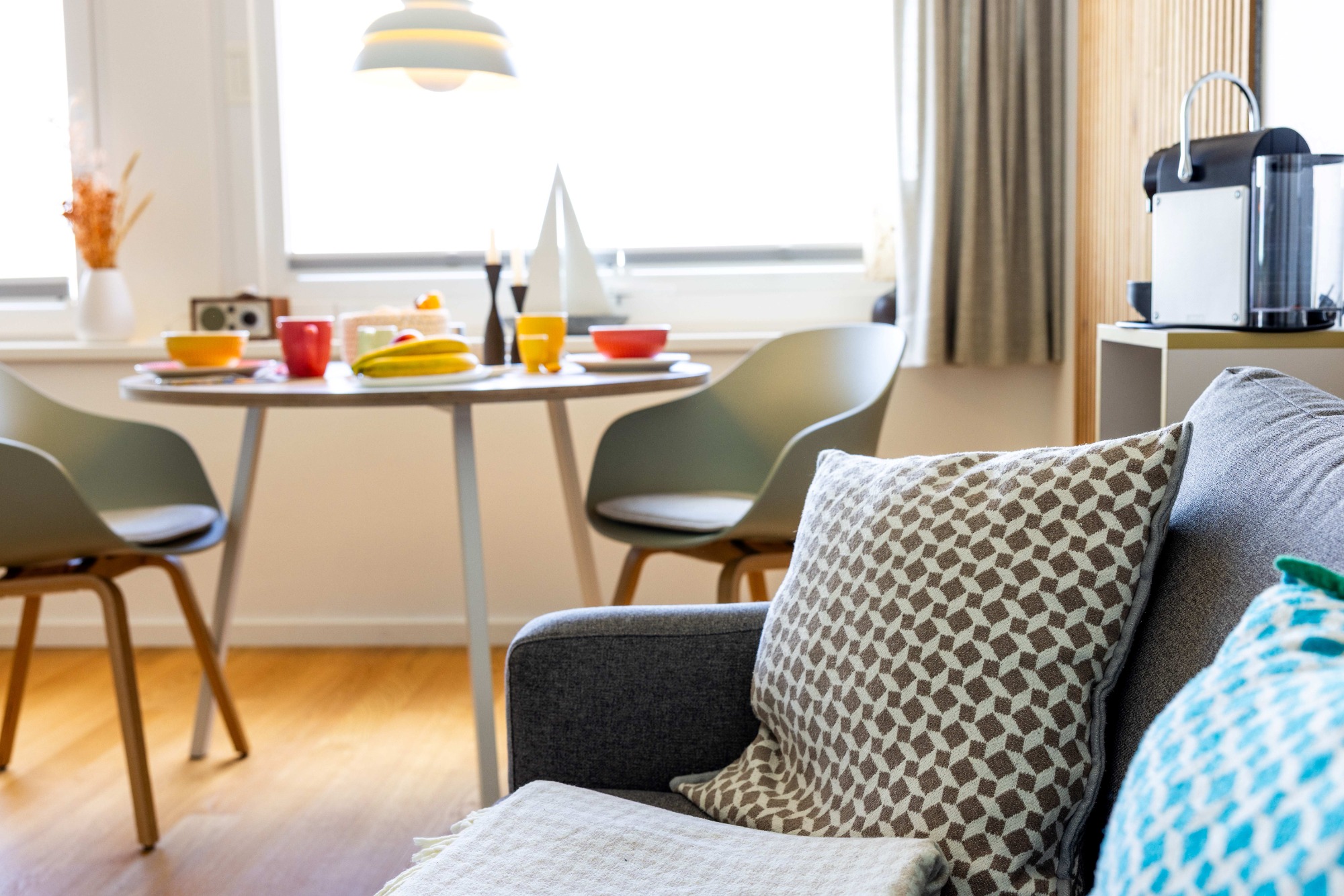 Guter Platz für eine Kaffeepause Helle Wohnküche mit Tisch, Stühlen und Sofa, gemütliche Dekoration und moderne Ausstattung.