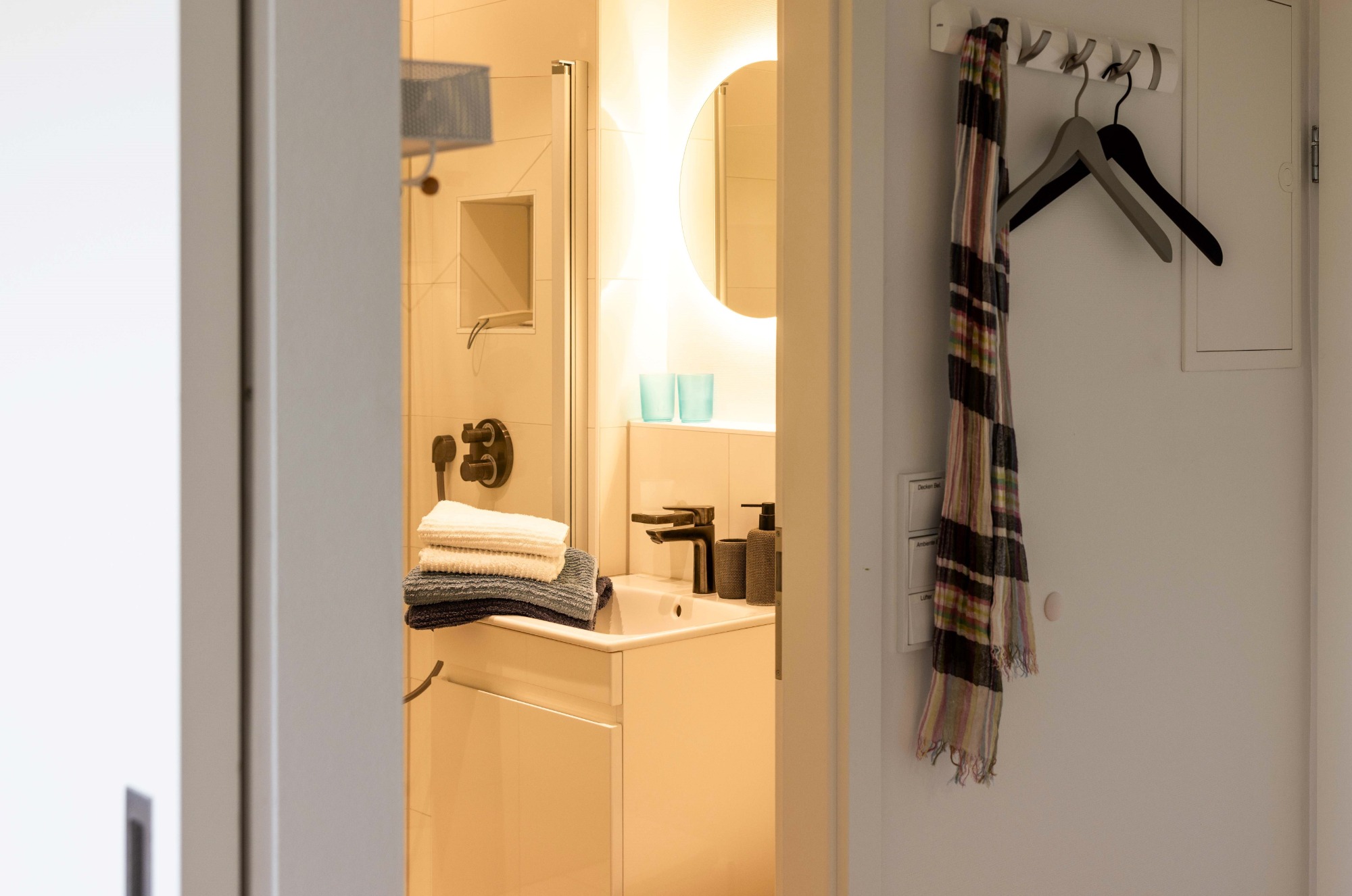 Exklusives Bad mit Ambiente Ein helles Bad mit Schrank, Handtüchern und einem Spiegel.