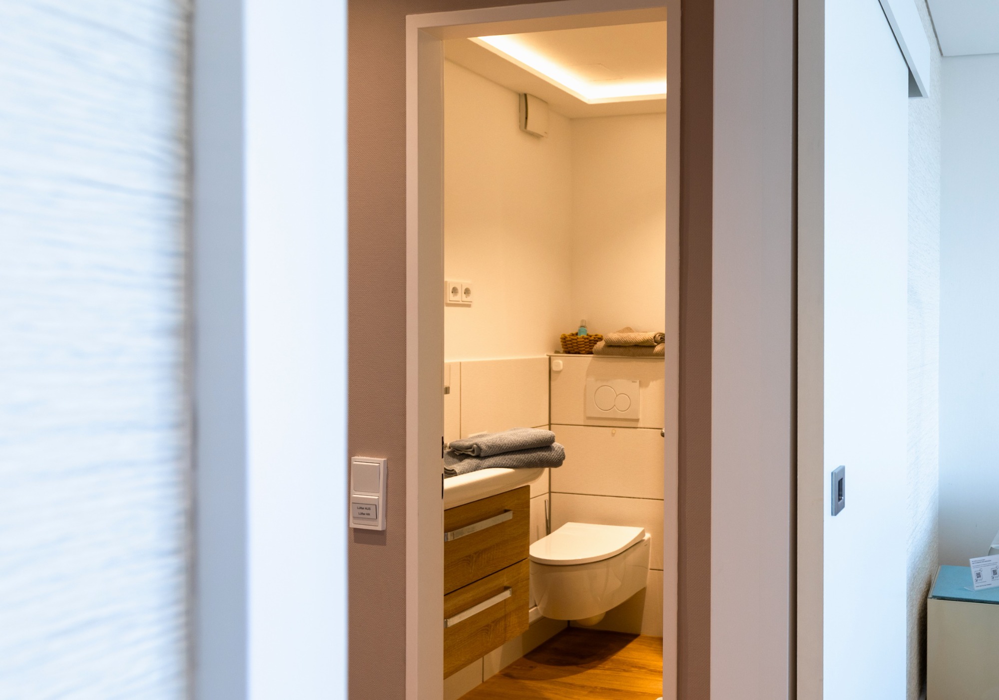 Duschbad Tür mit Blick auf ein modernes, helles Badezimmer.
