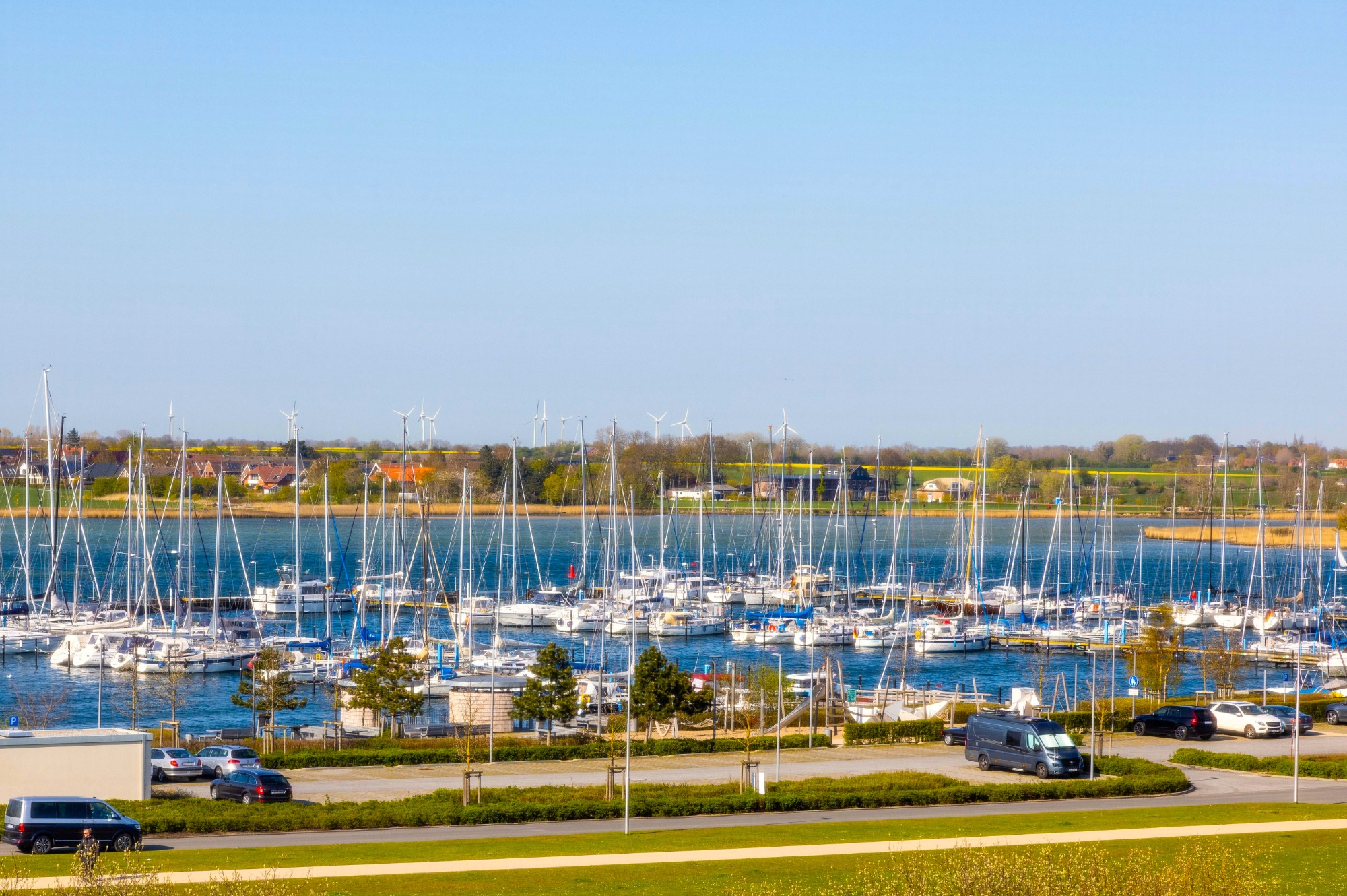 Panoramablick über Marina und grüne Insel Hafen mit vielen Yachten und einem klaren blauen Himmel. Grüne Flächen im Vordergrund.