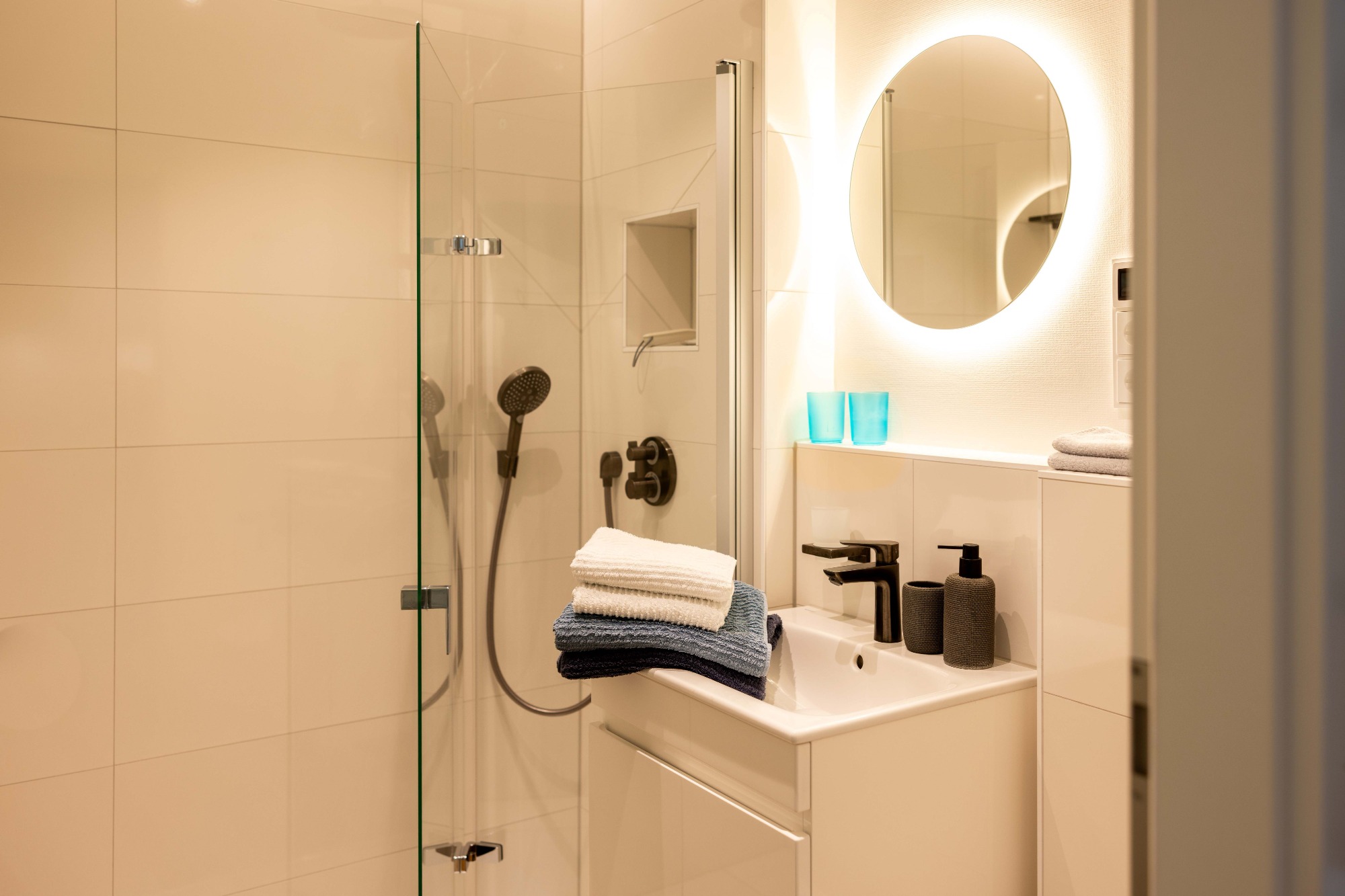 Großzügige Raindance Dusche Modernes Badezimmer mit Dusche, Spiegel und Handtüchern auf einem weißen Waschtisch.