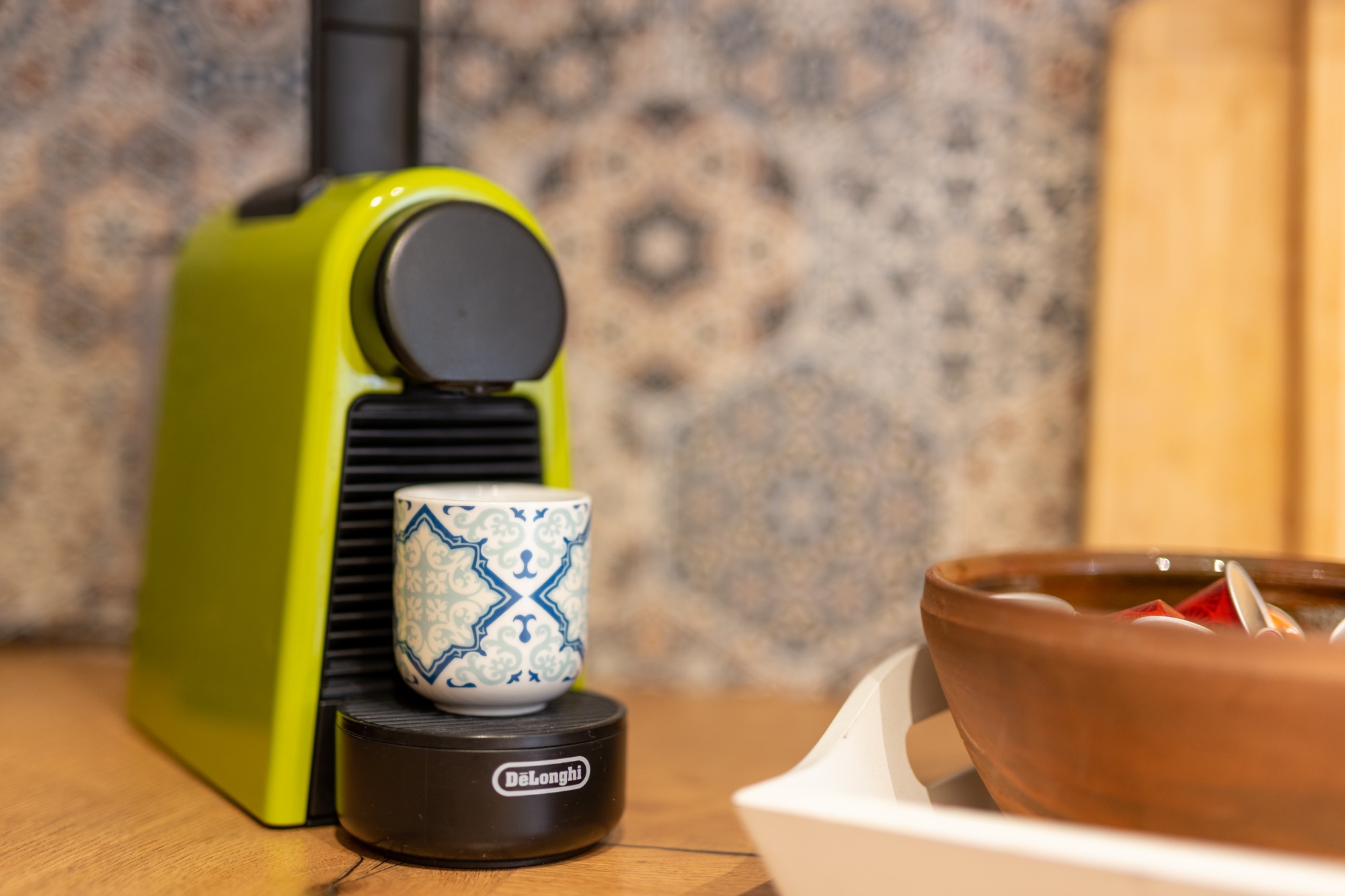 Kaffeepause zwischendurch Grüne Kaffeemaschine mit einer kleinen Tasse auf der Ablage. Hintergrund mit Mustern.