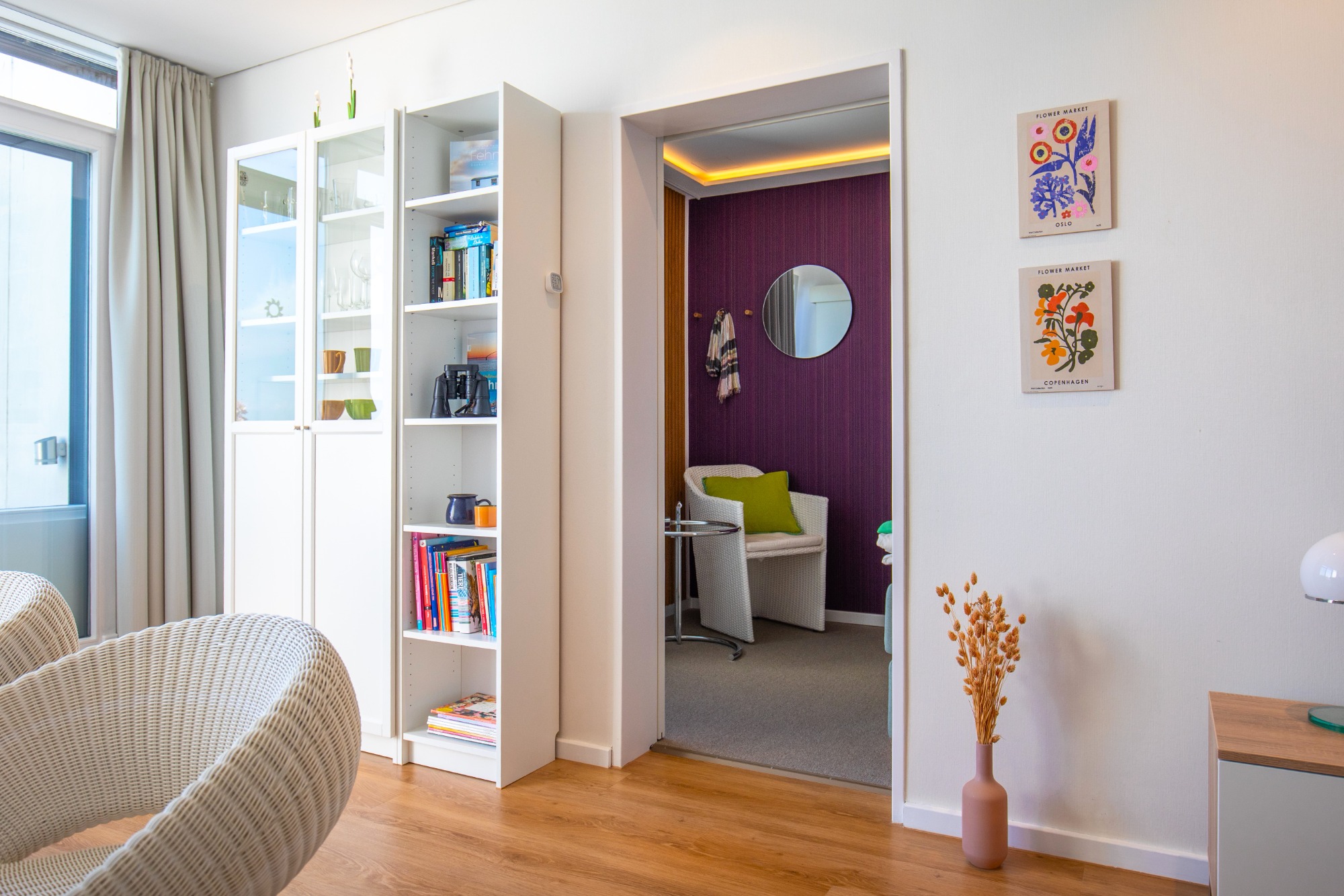 Extra Schlafzimmer mit Schiebetür Moderner Raum mit Bücherregal, klarem Blick auf einen lila Wandraum und gemütlichem Sitzbereich.