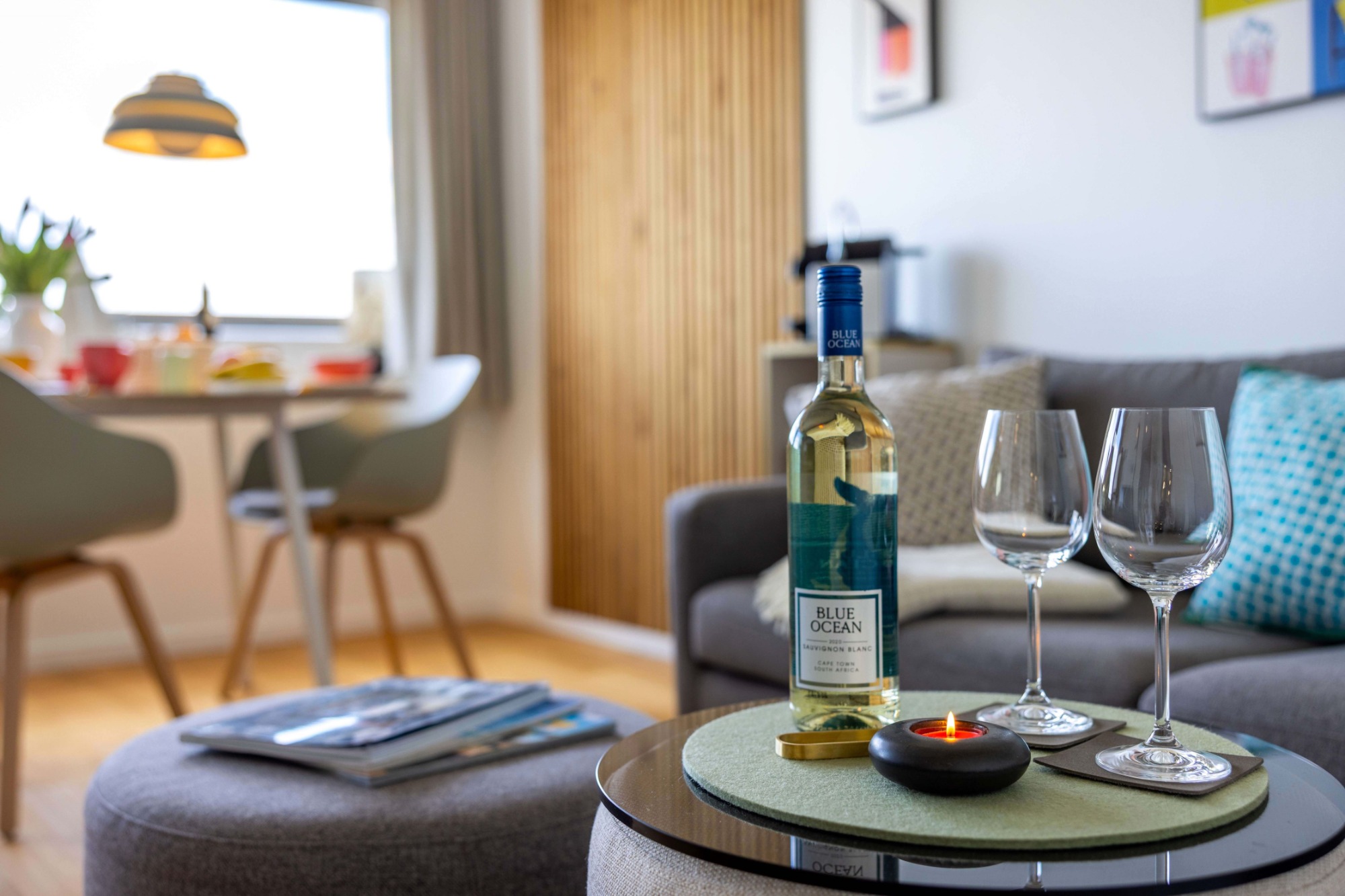 Lass´ den Strandtag einfach ausklingen ! Wohnzimmer mit einem Tisch, Weinflasche, Gläsern und einem gemütlichen Ambiente.